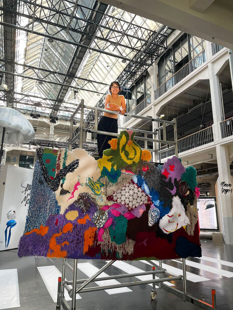Isabella Panigada in front of a work of art by Safer Space BIPoC HfG